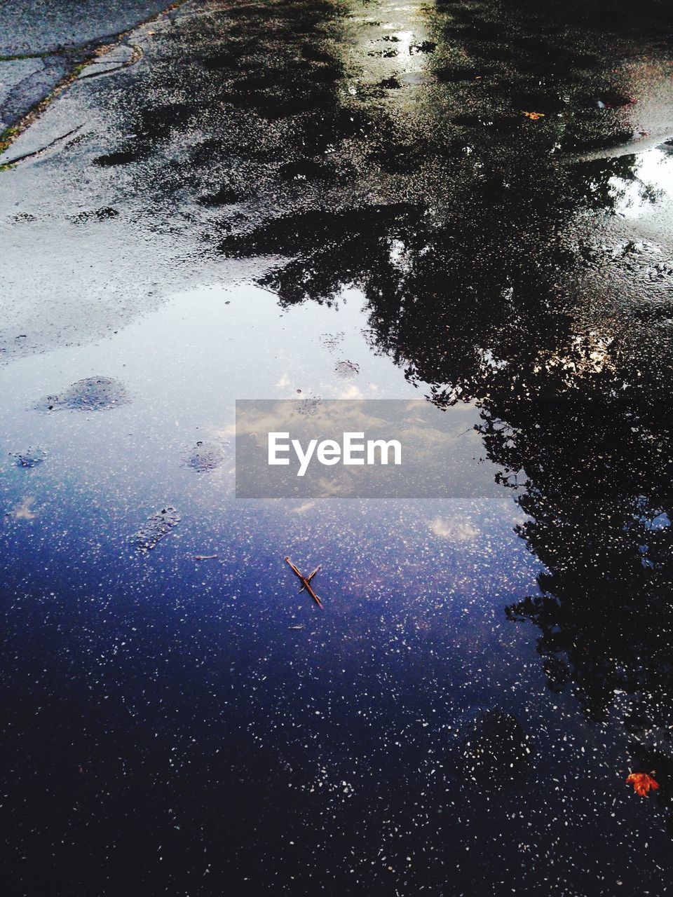 Reflection of sky in puddle on street