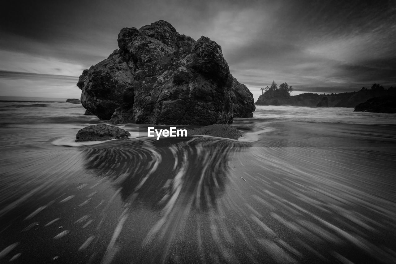 Rock formation on beach against sky