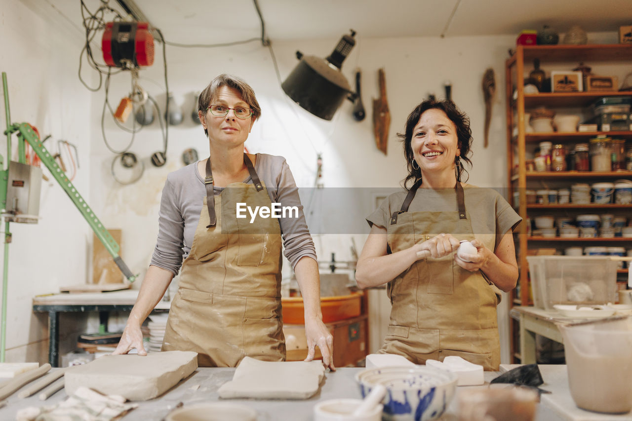 Happy entrepreneur with colleague working together at ceramics workshop