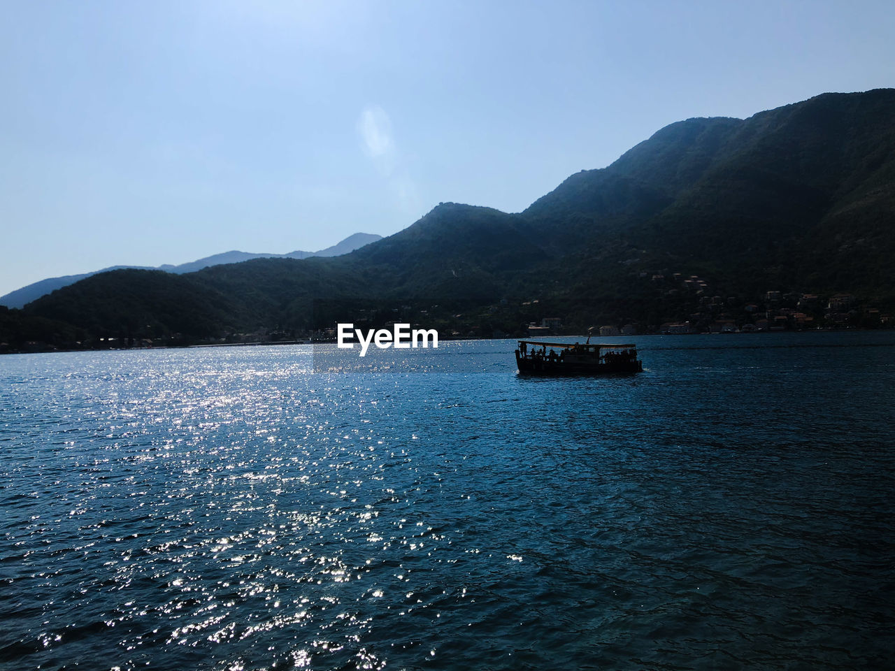 BOAT SAILING ON SEA AGAINST MOUNTAINS