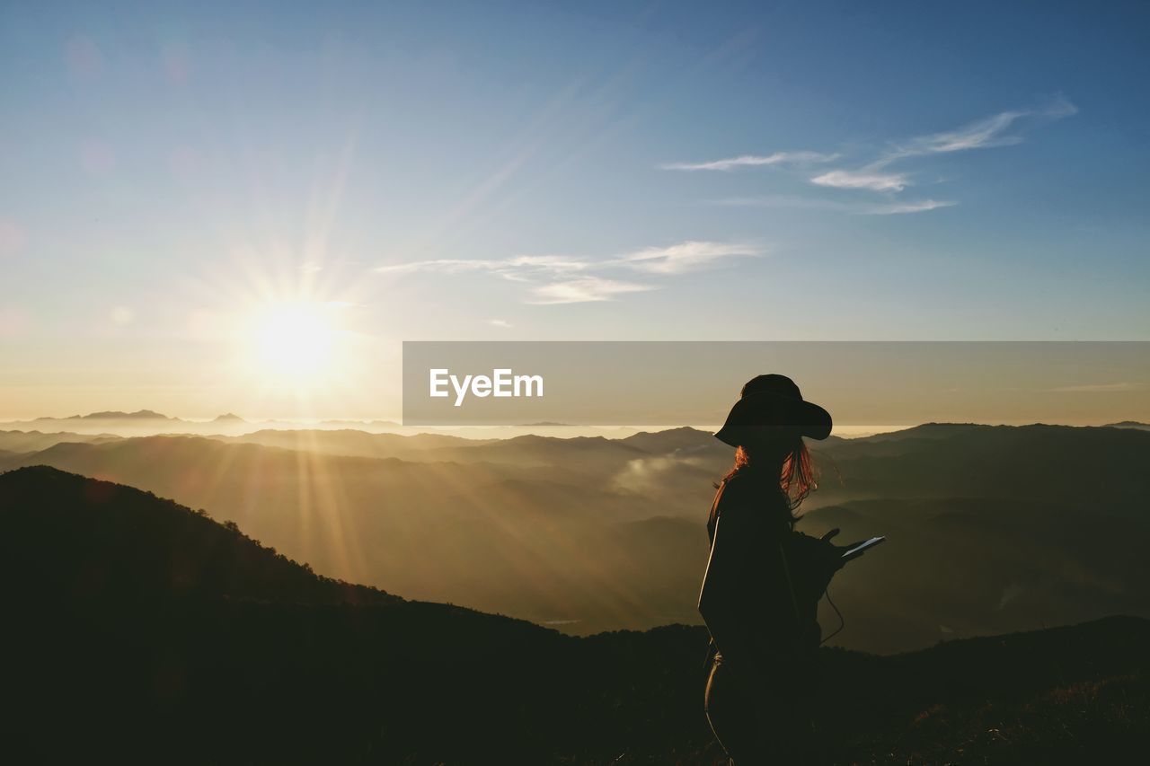 Silhouette woman standing on mountain against sky during sunset