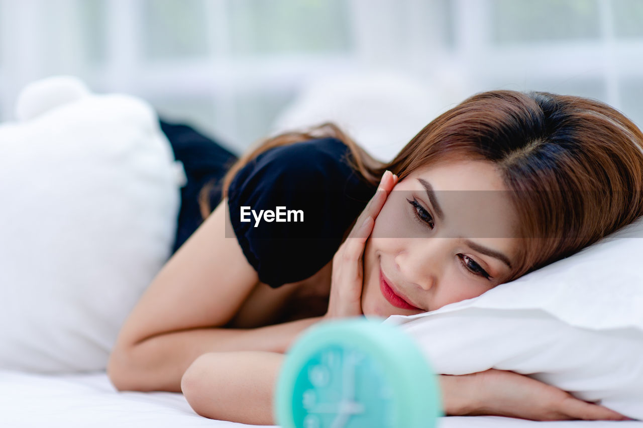 PORTRAIT OF SMILING WOMAN LYING ON BED