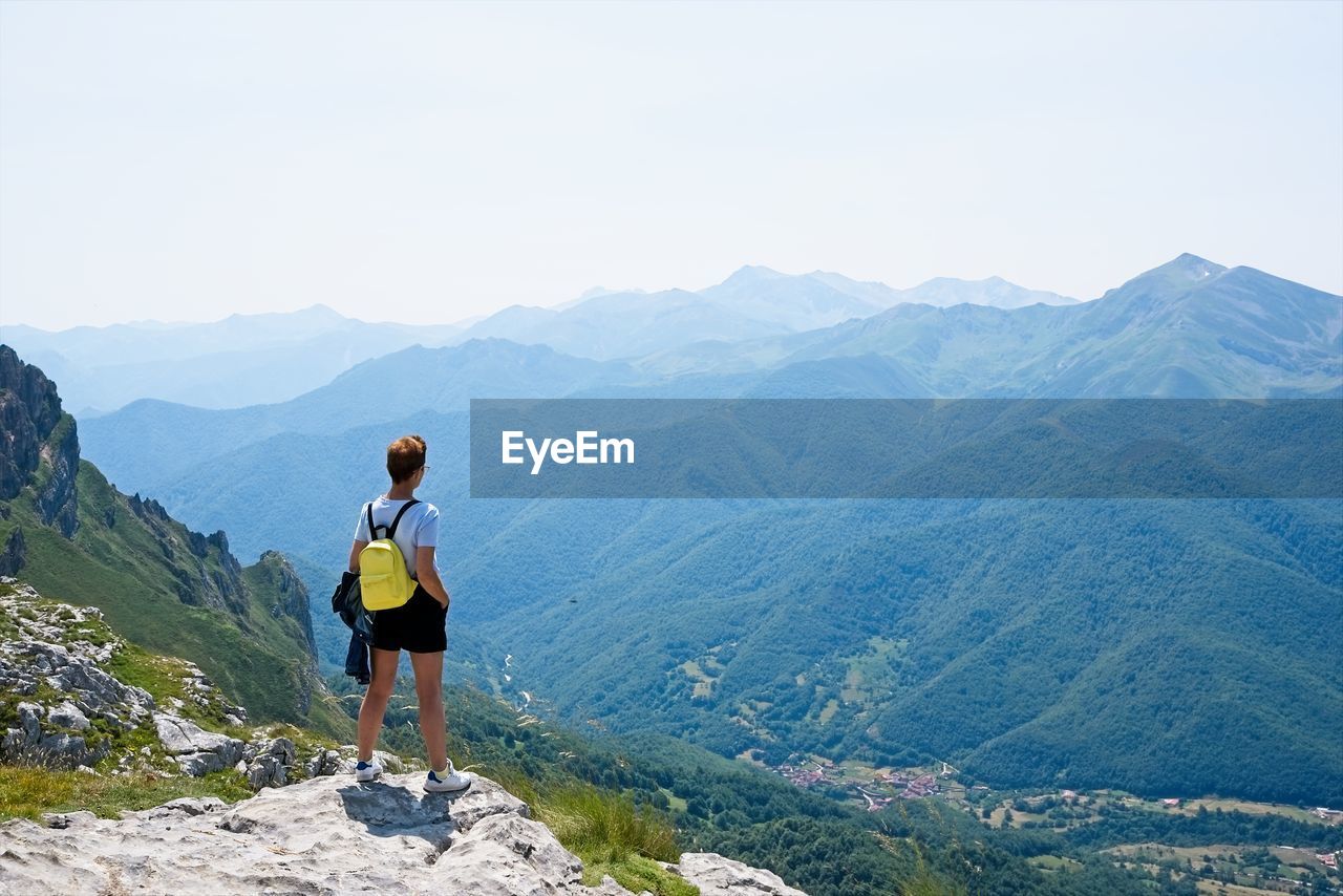 A woman looks at the landscape from the top of a mountain