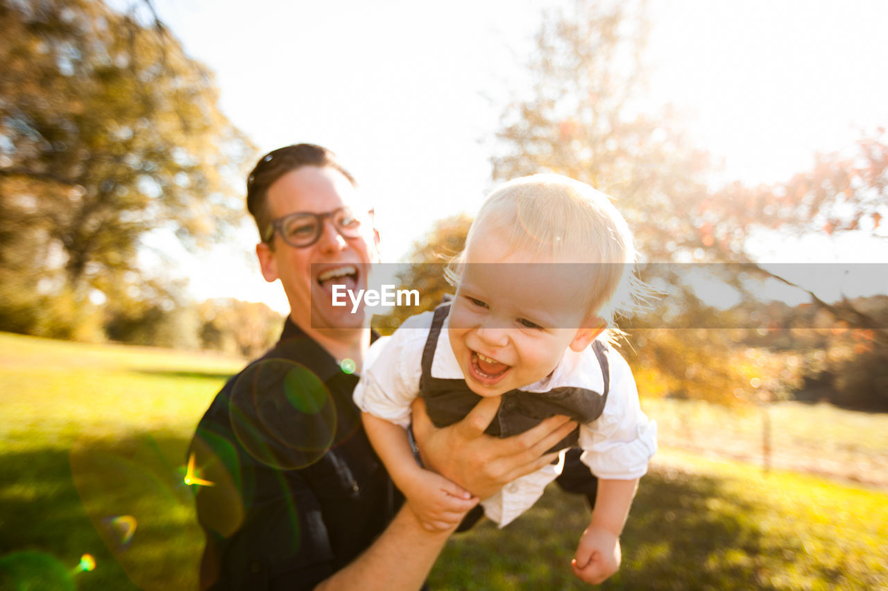 Cheerful father holding son at park