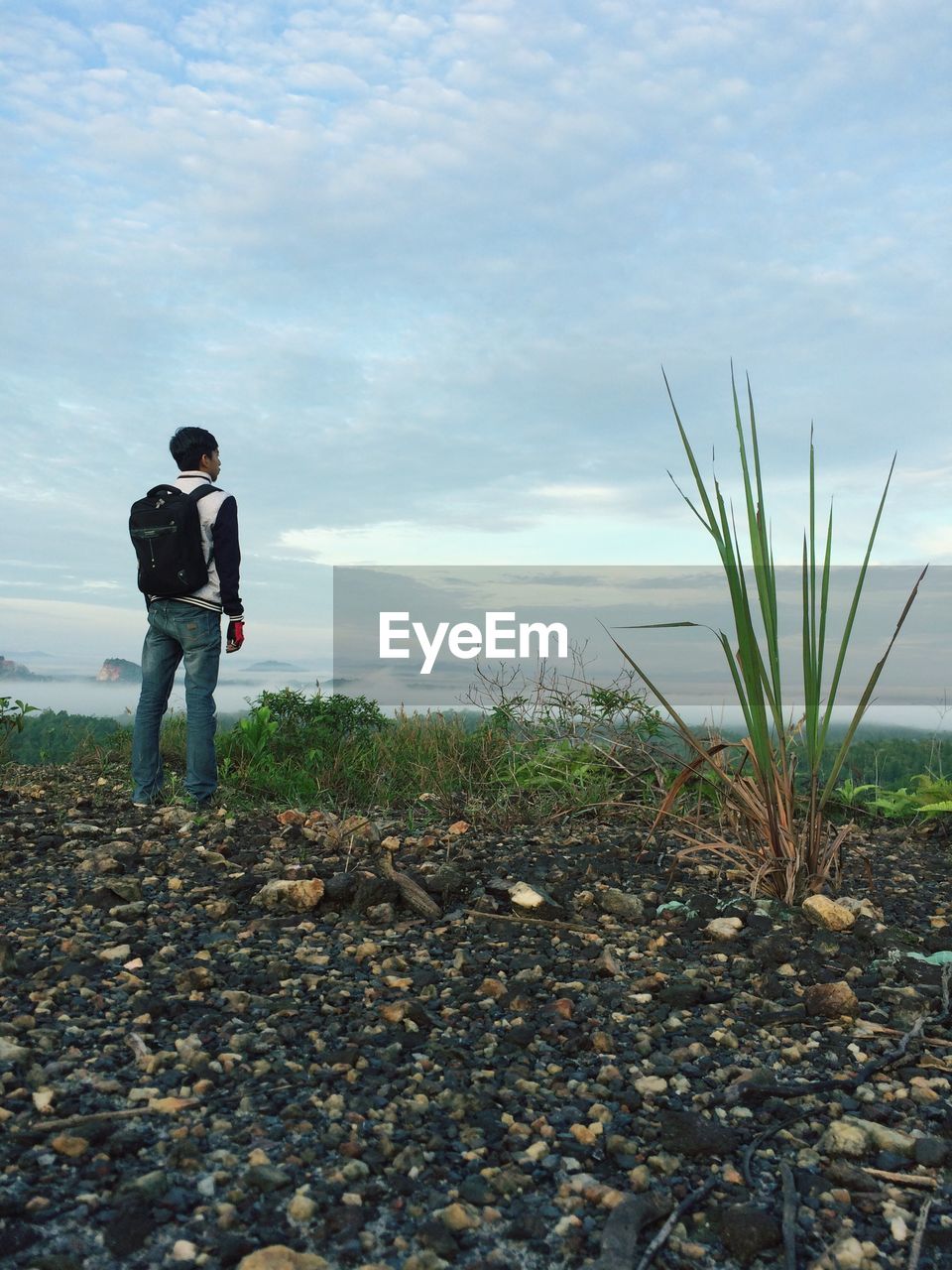 Full length of young man standing on field against sky