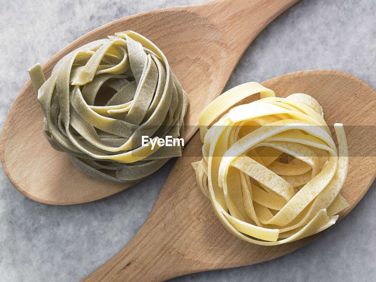 High angle view of tagliatelle pasta on wooden spoon at table