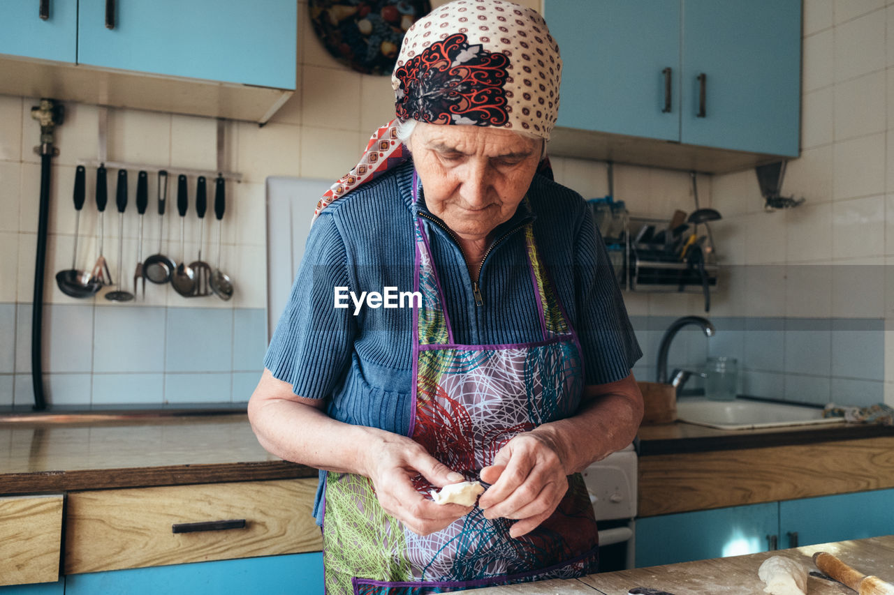 Senior woman preparing food by table at home