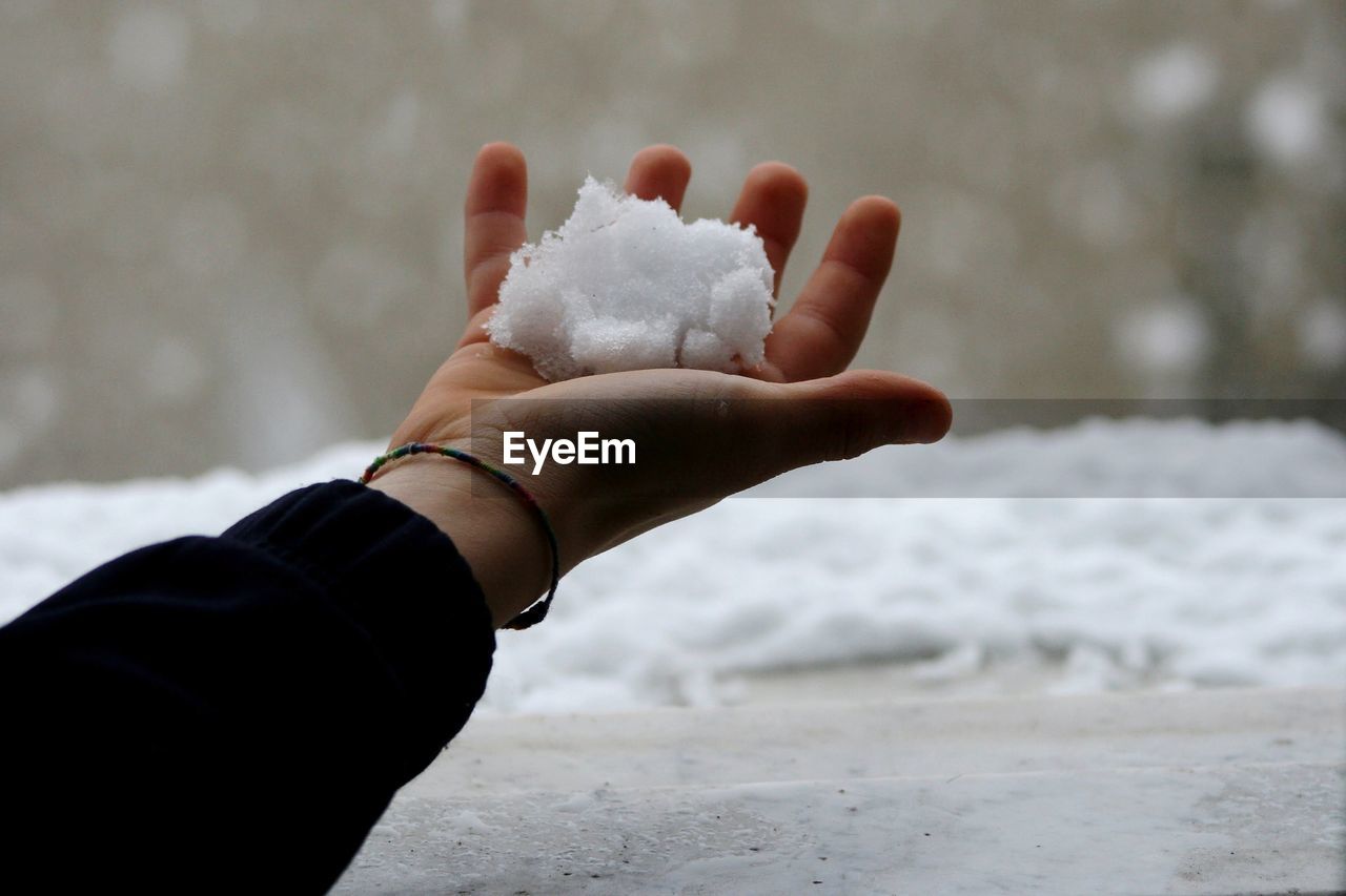 Cropped hand of child holding snow outdoors