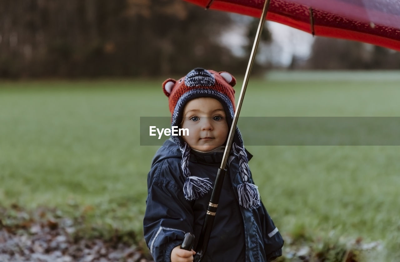 Portrait of girl holding umbrella while standing at park