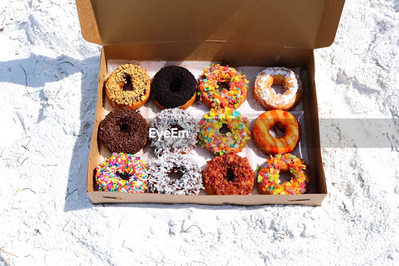 High angle view of donuts in box on sand