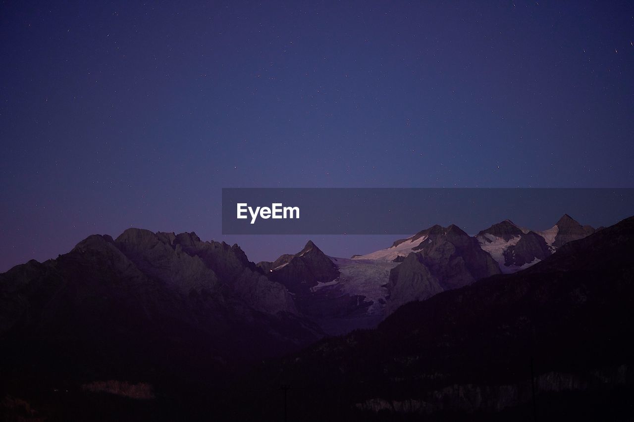 Scenic view of mountains against clear sky at night