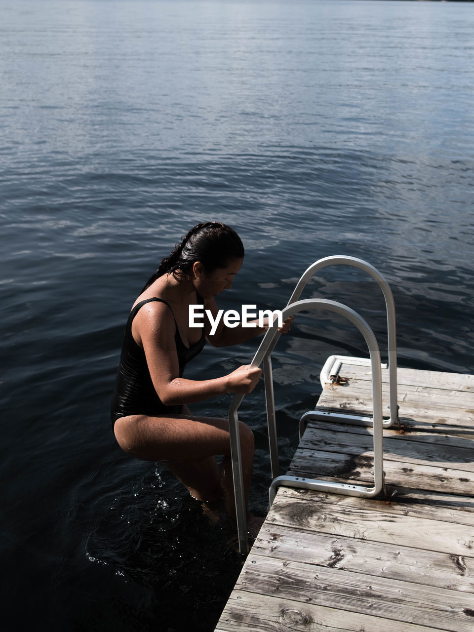 High angle view of woman in swimwear climbing ladder at lake