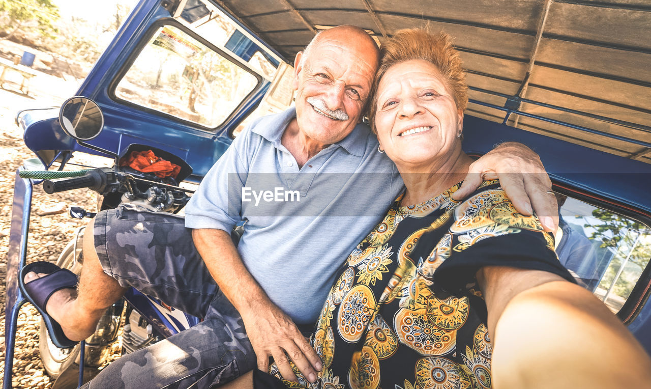 Portrait of smiling couple sitting on vehicle