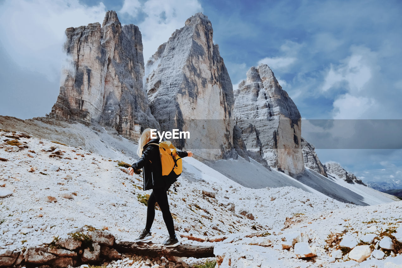 Female hiker balancing on tree trunks against mountain range 