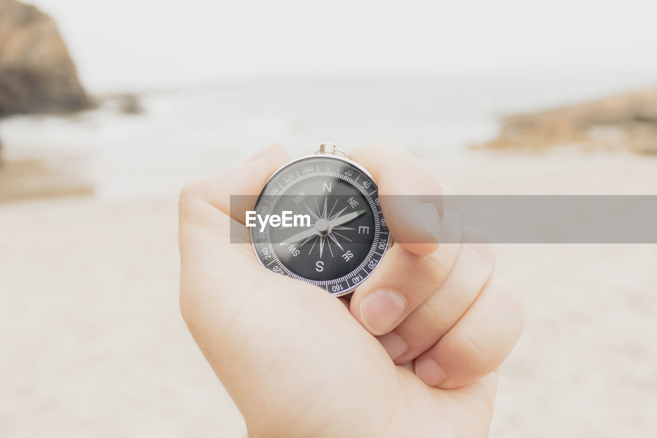 cropped hand of person holding navigational compass