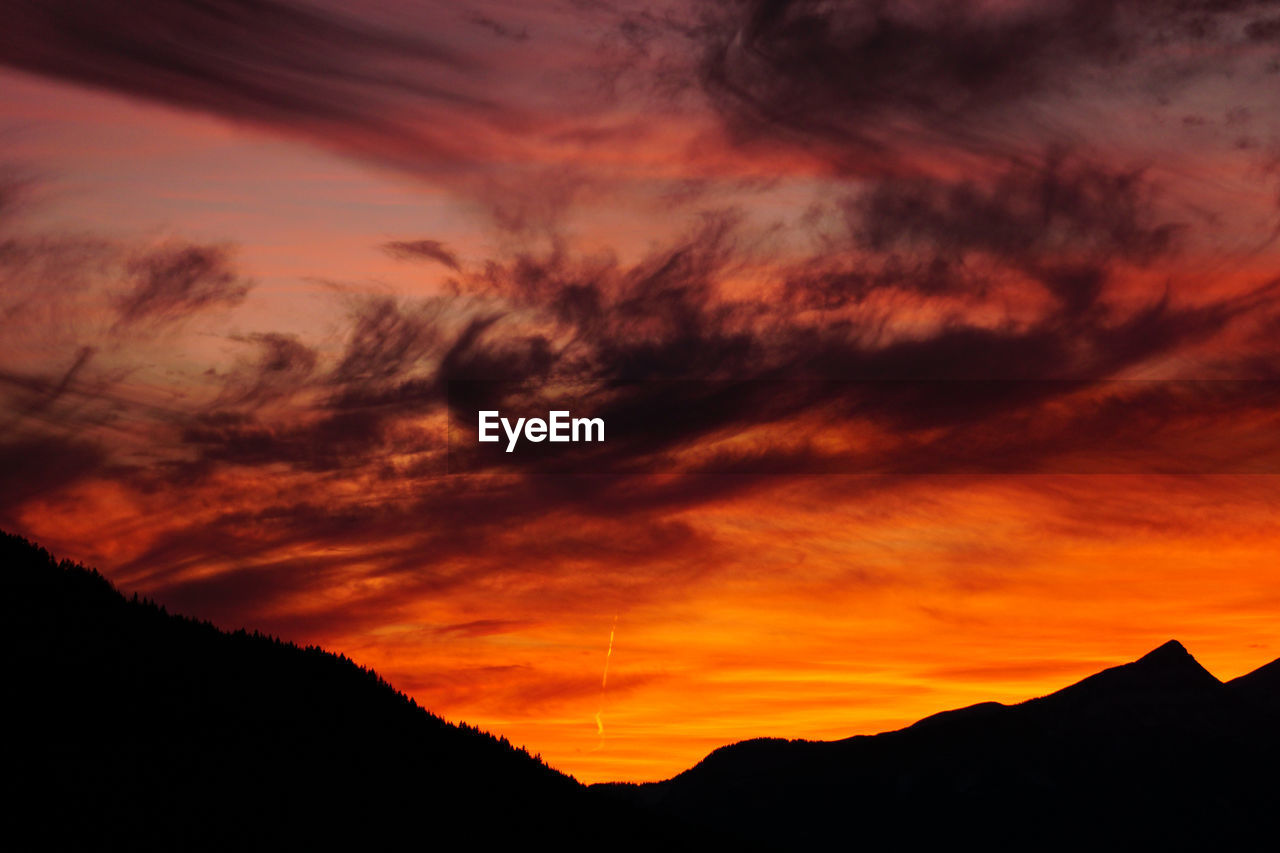 LOW ANGLE VIEW OF DRAMATIC SKY OVER SILHOUETTE MOUNTAINS