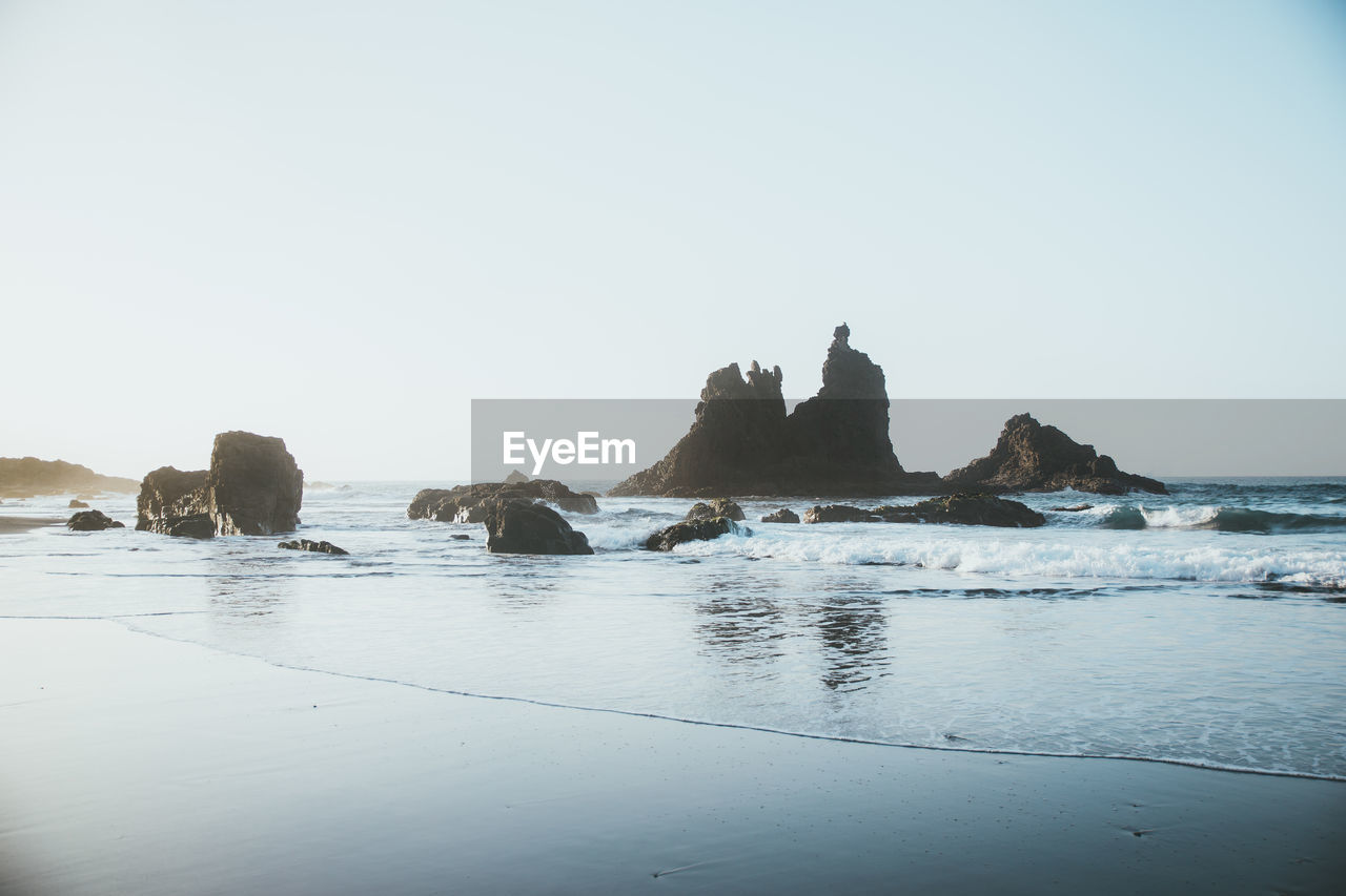 Rocks on beach against clear sky