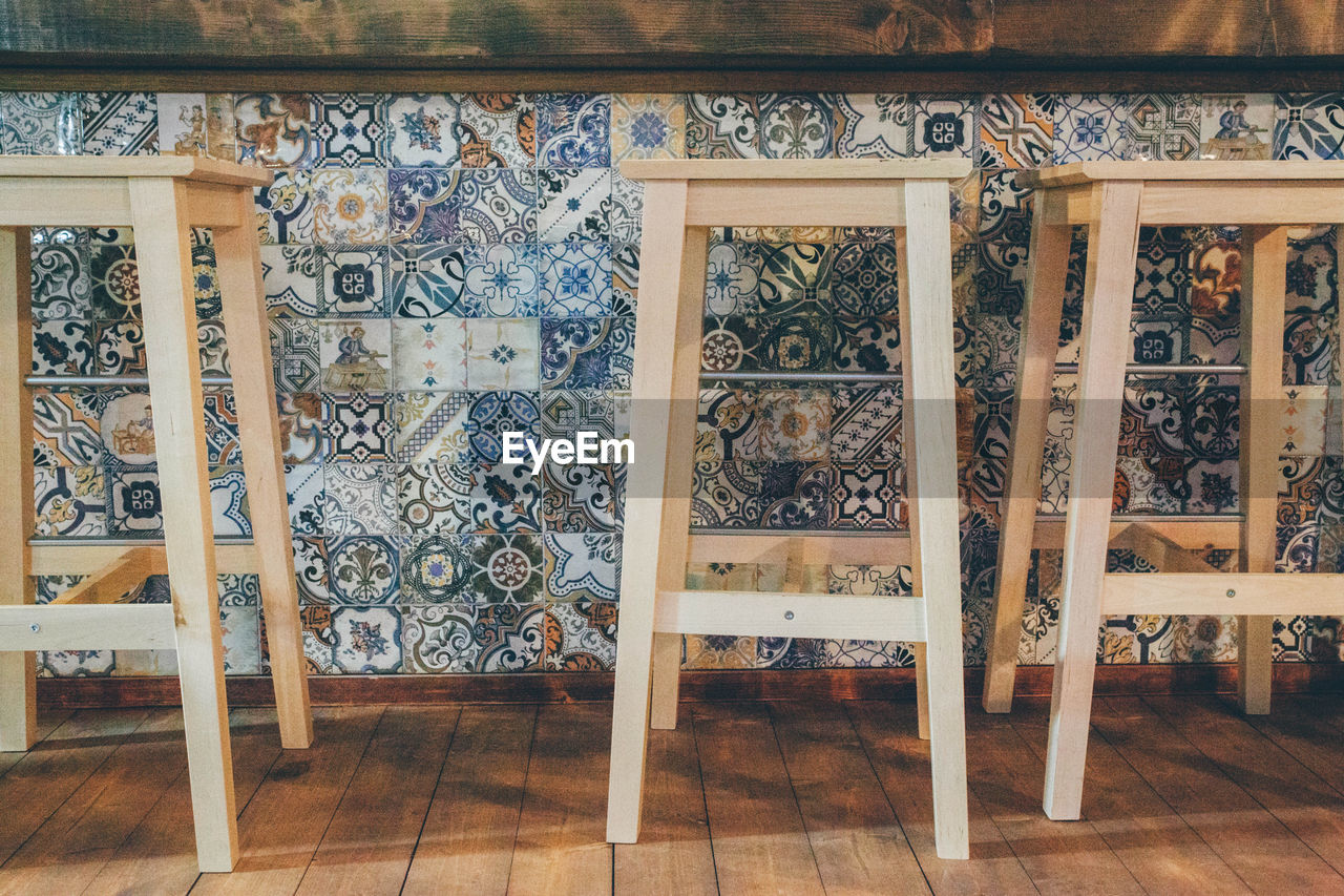 Wooden stools against mosaic counter at bar