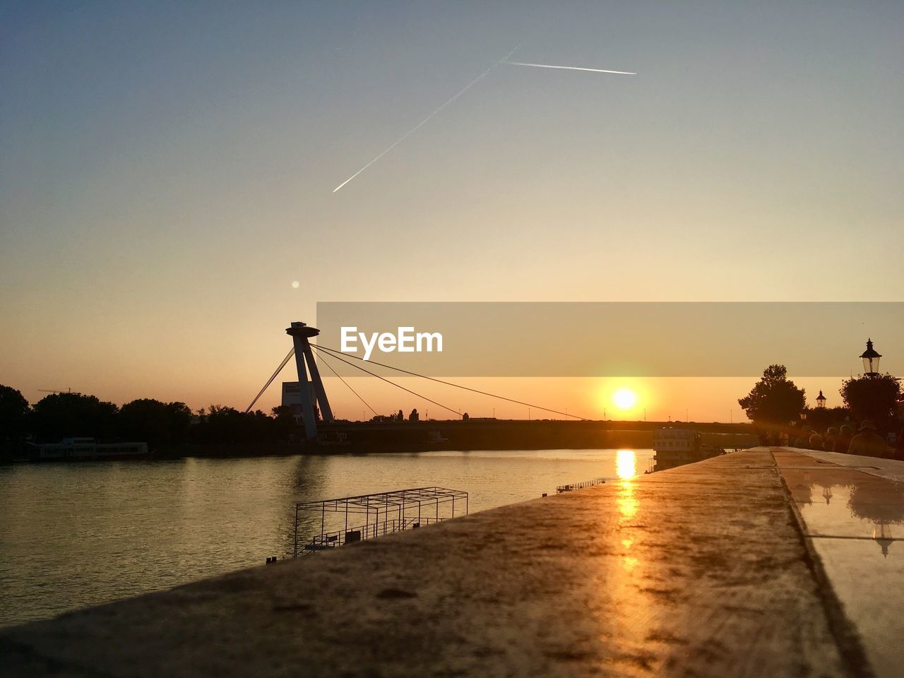 BRIDGE OVER RIVER AGAINST SKY AT SUNSET