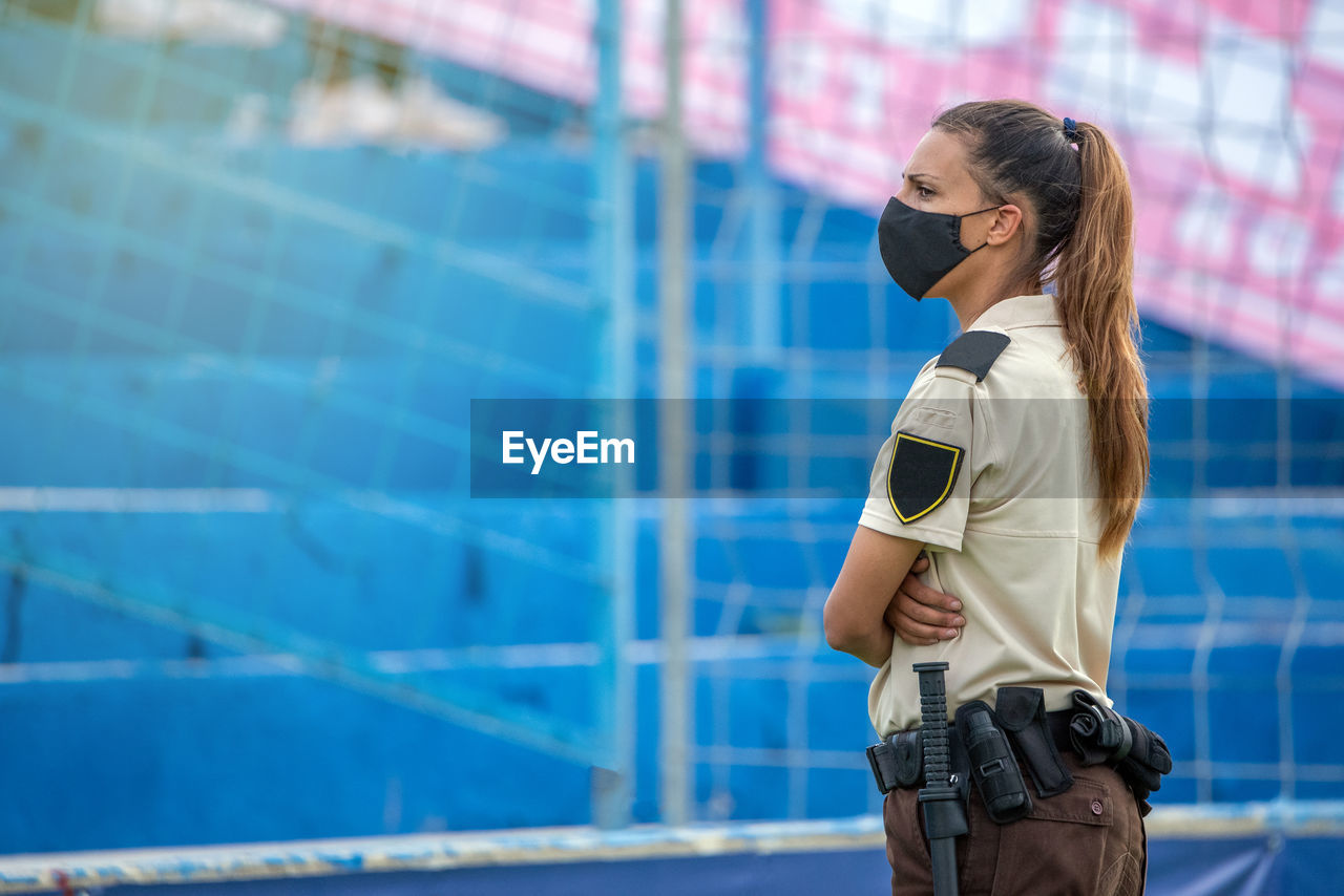 Side view of security person wearing mask standing at stadium