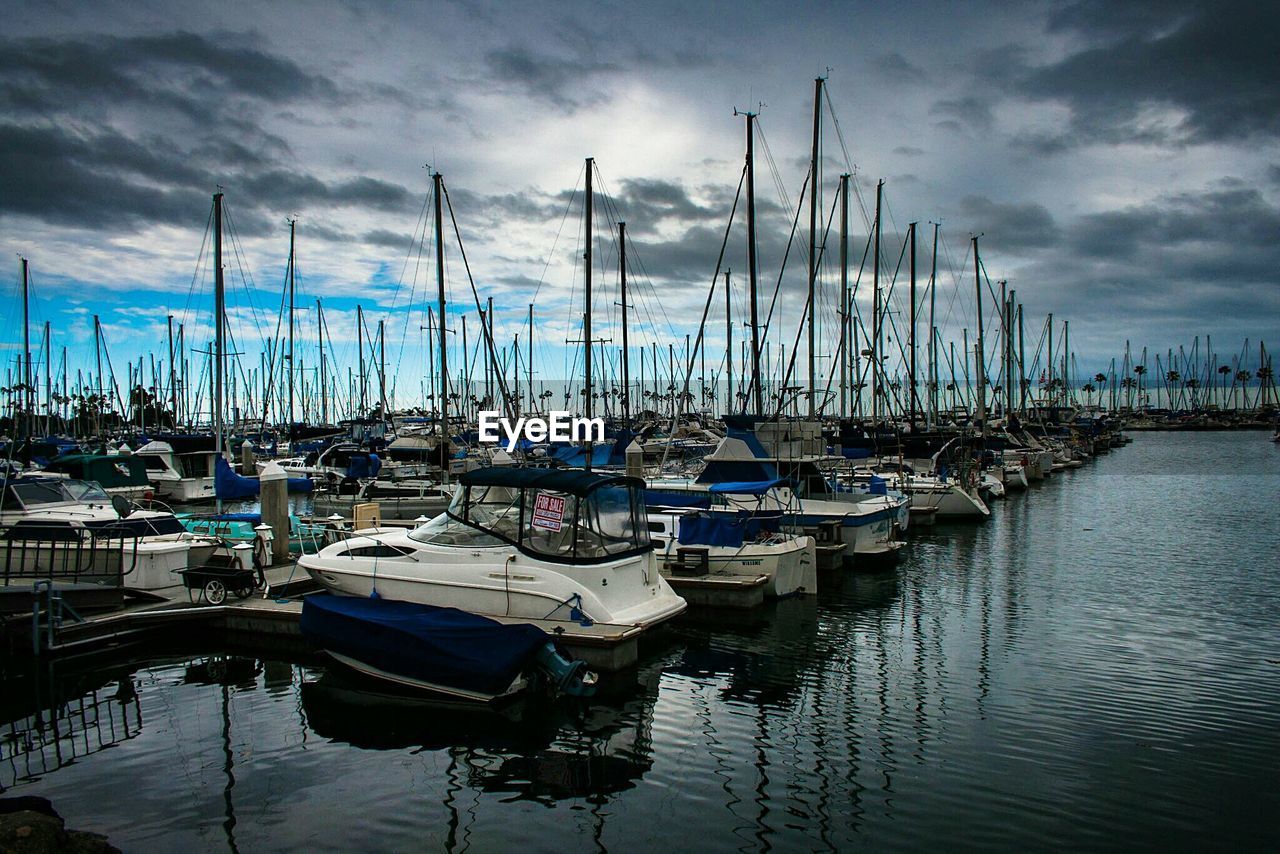 Boats moored in sea against cloudy sky