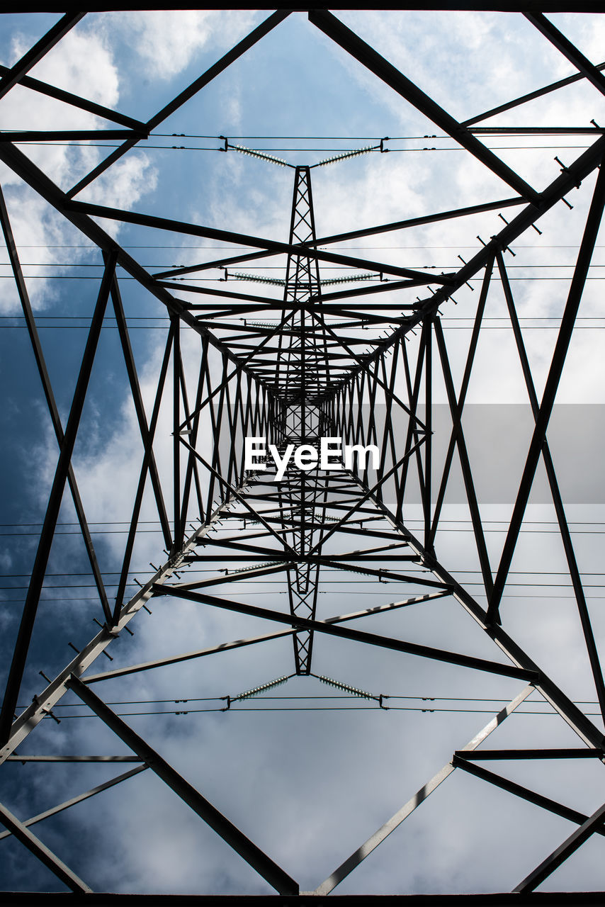 Directly below shot of electricity pylon against cloudy sky