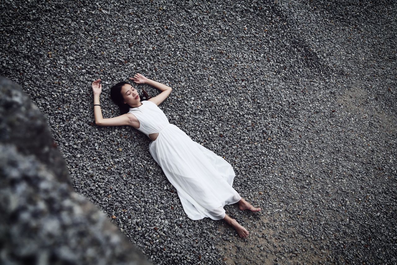 High angle view of young woman lying on gravel