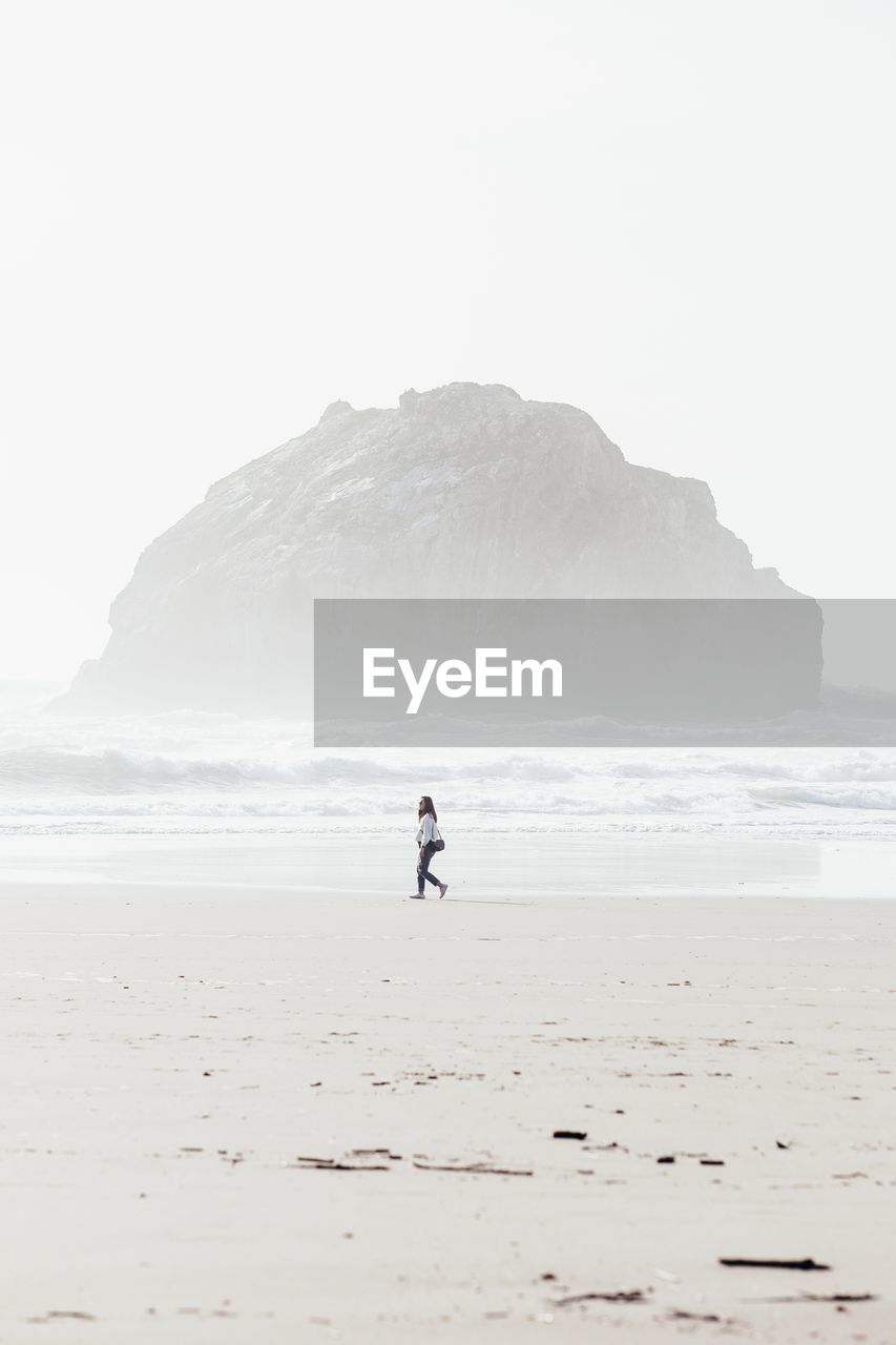 WOMAN ON BEACH AGAINST CLEAR SKY