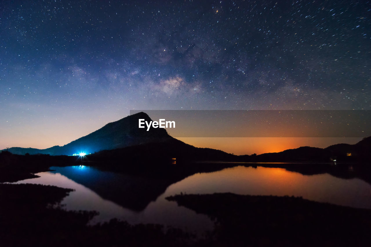 Scenic view of lake and mountains against sky at night