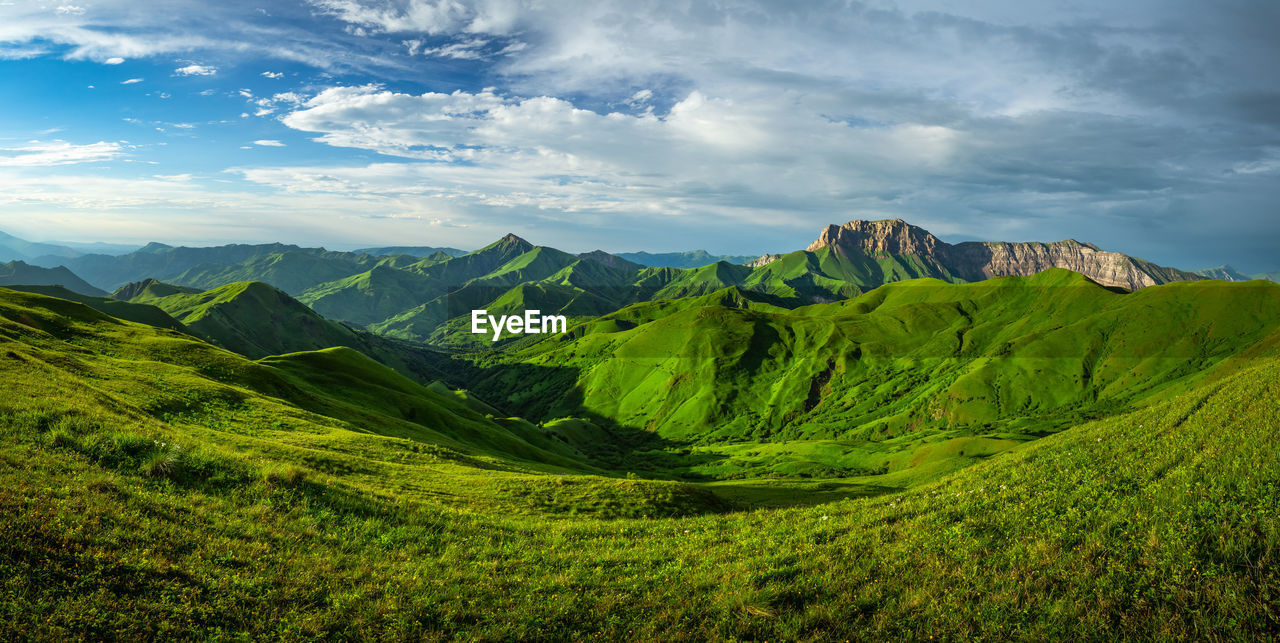 Panoramic view of green landscape and mountains against sky