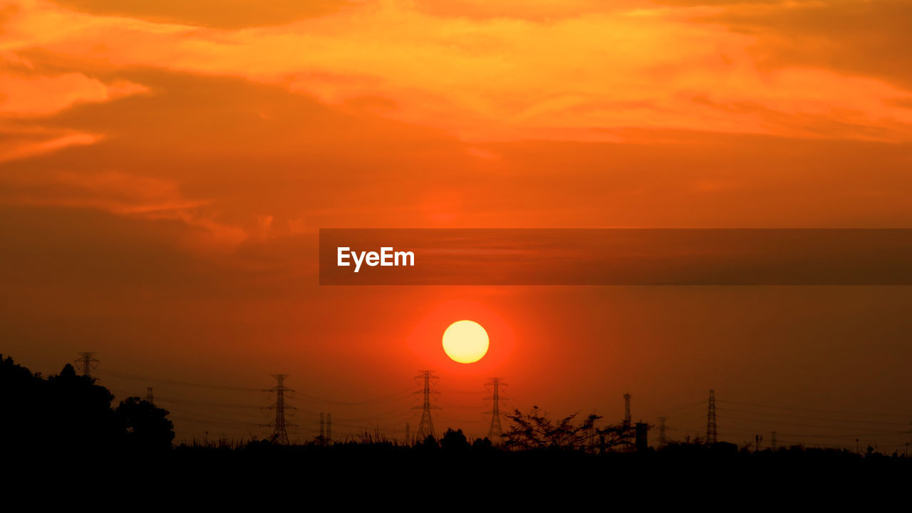 Silhouette electricity pylon against romantic sky at sunset