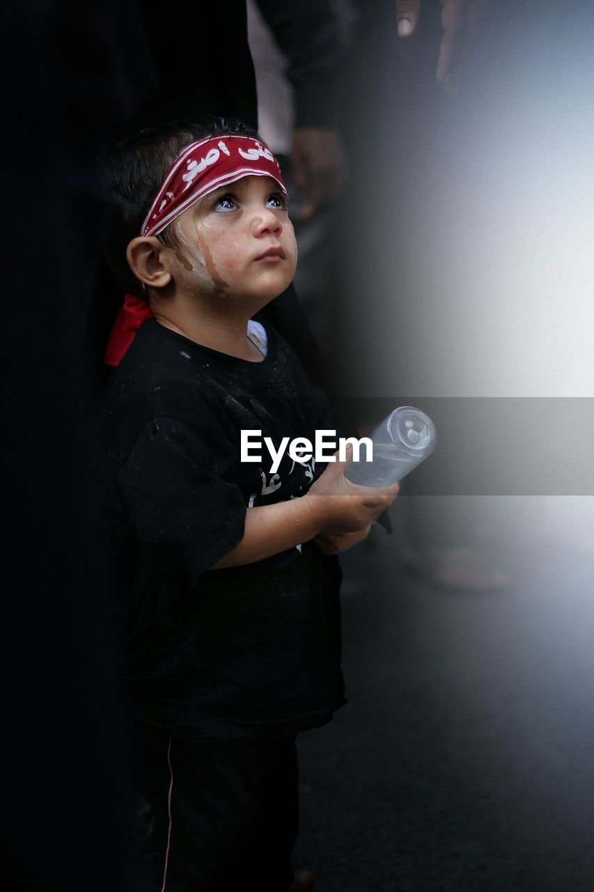 Cute boy with face paint looking up during event