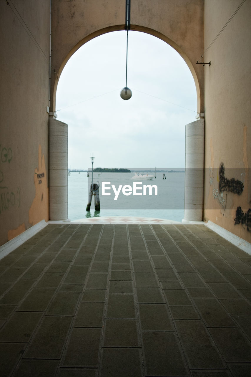 BUILDINGS BY SEA AGAINST SKY SEEN THROUGH ARCH