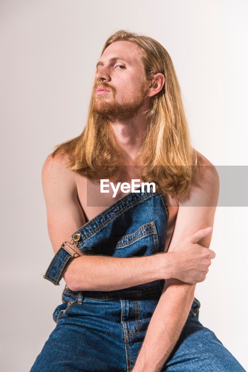 PORTRAIT OF YOUNG MAN STANDING OVER WHITE BACKGROUND