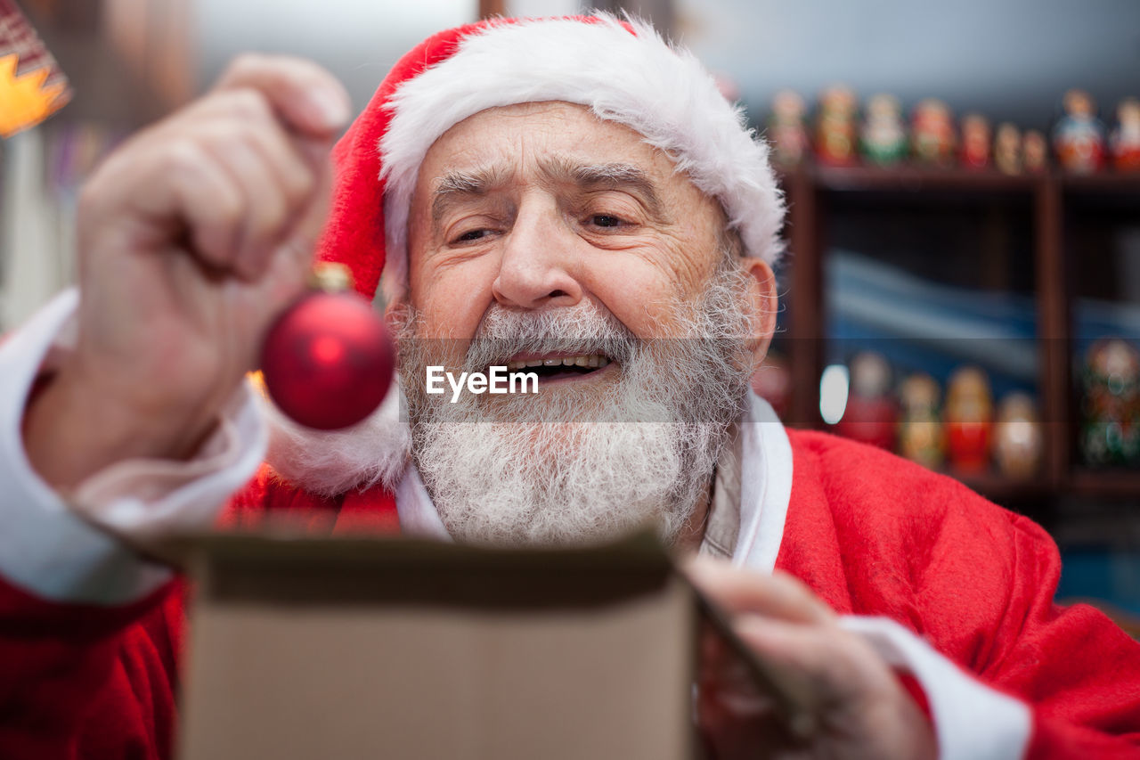 Senior man in santa claus costume sitting at home