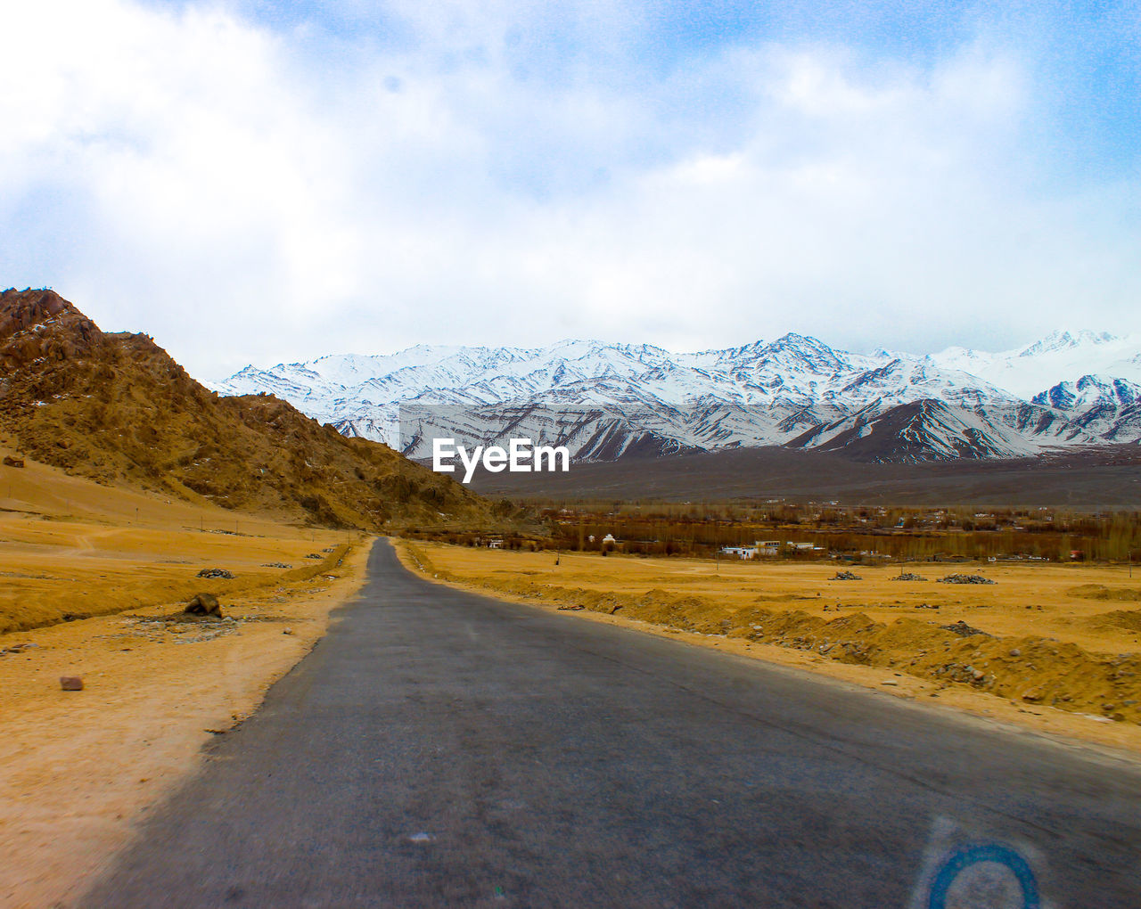 Road amidst snowcapped mountains against sky