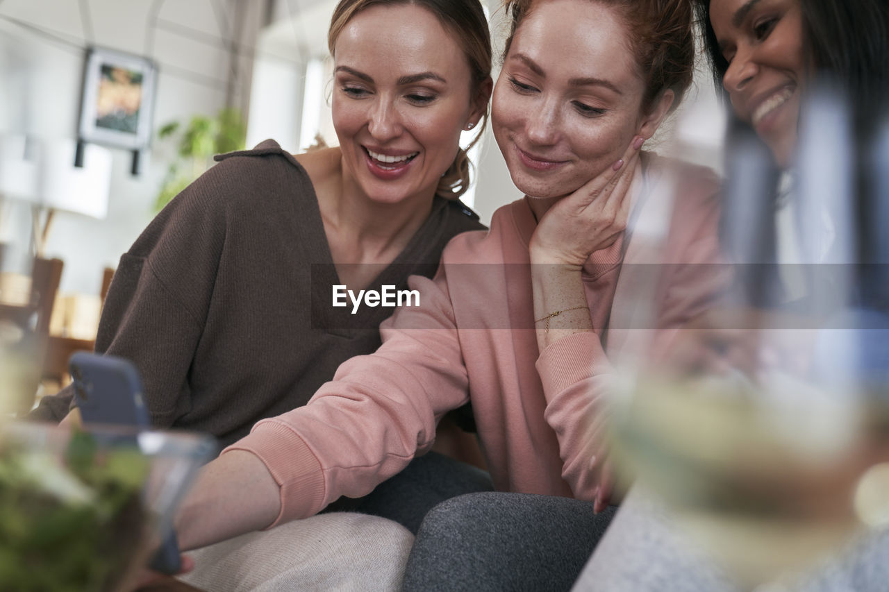 Smiling females looking at mobile phone at home