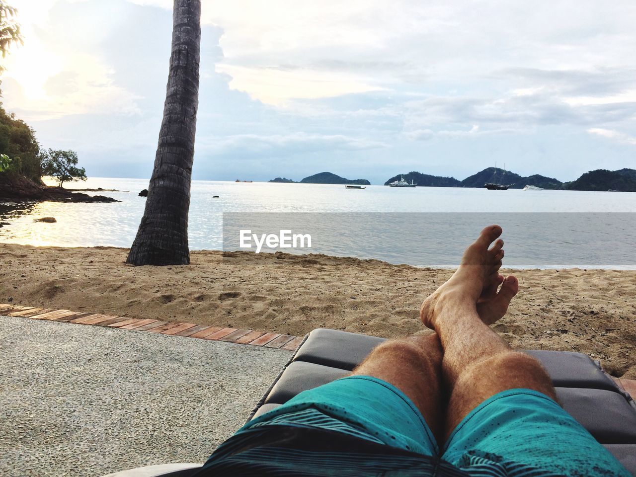 LOW SECTION OF WOMAN LYING ON BEACH