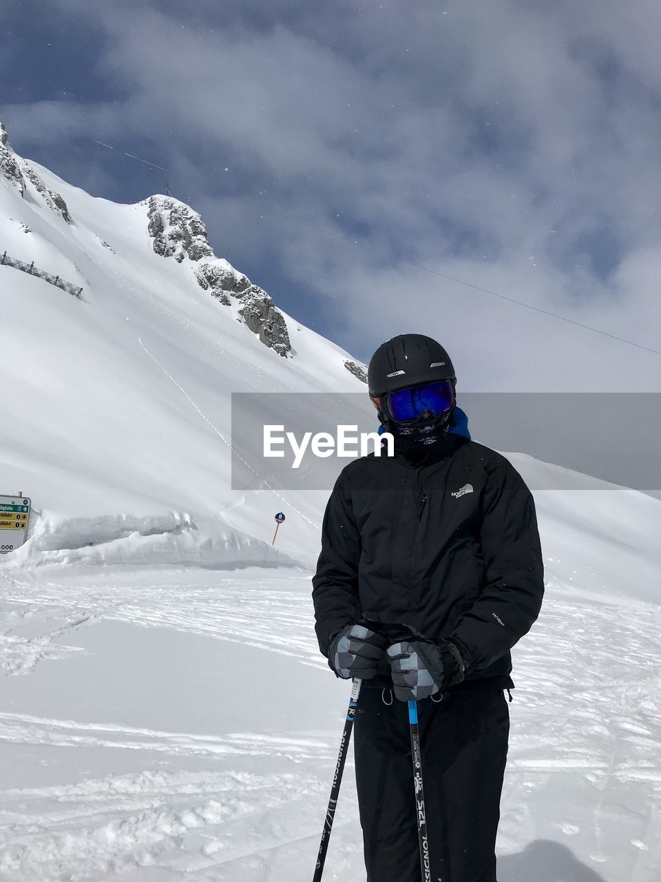 MAN ON SNOWCAPPED MOUNTAIN AGAINST SKY