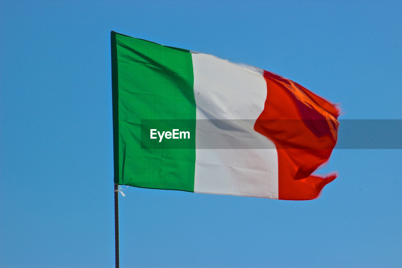 LOW ANGLE VIEW OF FLAGS AGAINST BLUE SKY