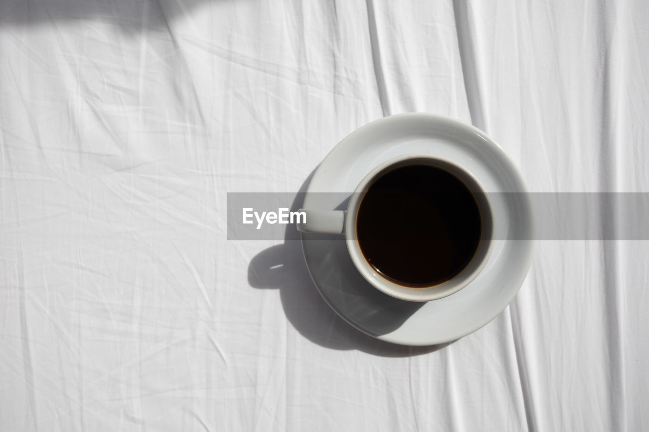 HIGH ANGLE VIEW OF COFFEE CUP ON WHITE TABLE