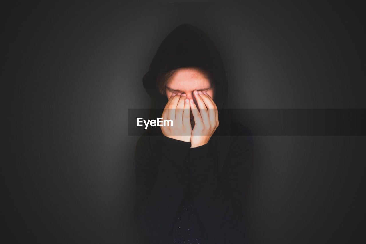 Person with eyes covered by hands against gray background