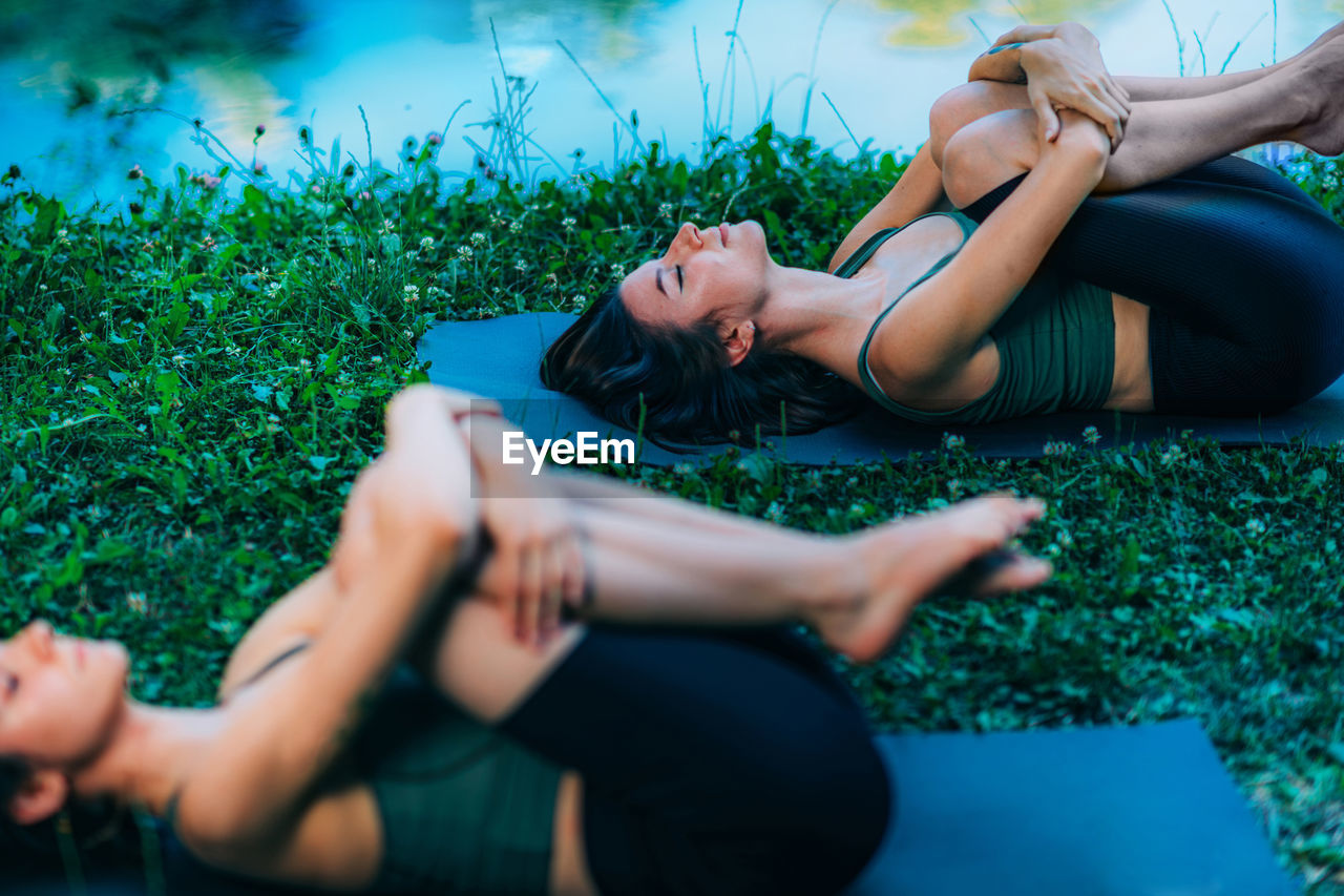 Yoga women by the water. wind relieving pose.