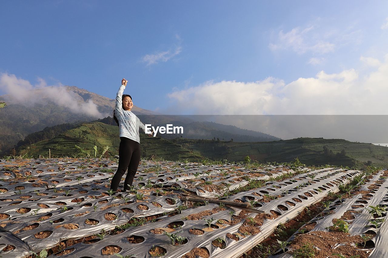 Rear view of man standing on mountain against sky