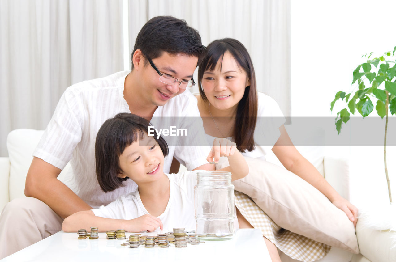 Smiling family with coins on table at home