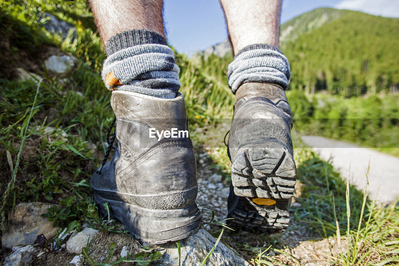 one person, low section, human leg, shoe, footwear, plant, limb, grass, nature, human limb, green, adult, tree, day, human foot, leisure activity, outdoors, land, lifestyles, dirt, standing, environment, hiking, spring, sock, close-up, landscape