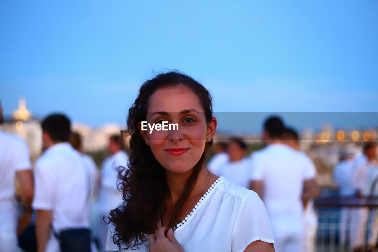 PORTRAIT OF SMILING WOMAN AGAINST SKY