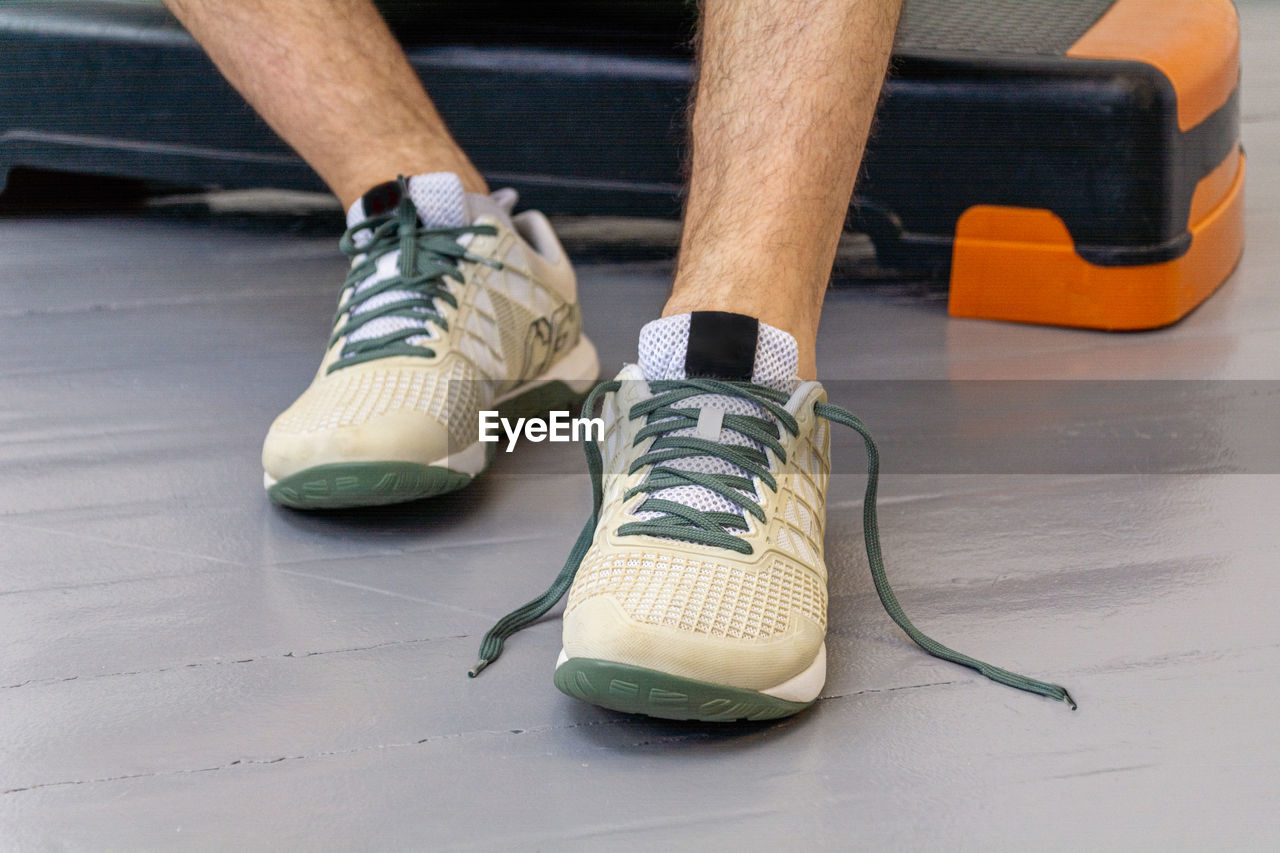 Close-up of men's legs in sneakers with green laces. 