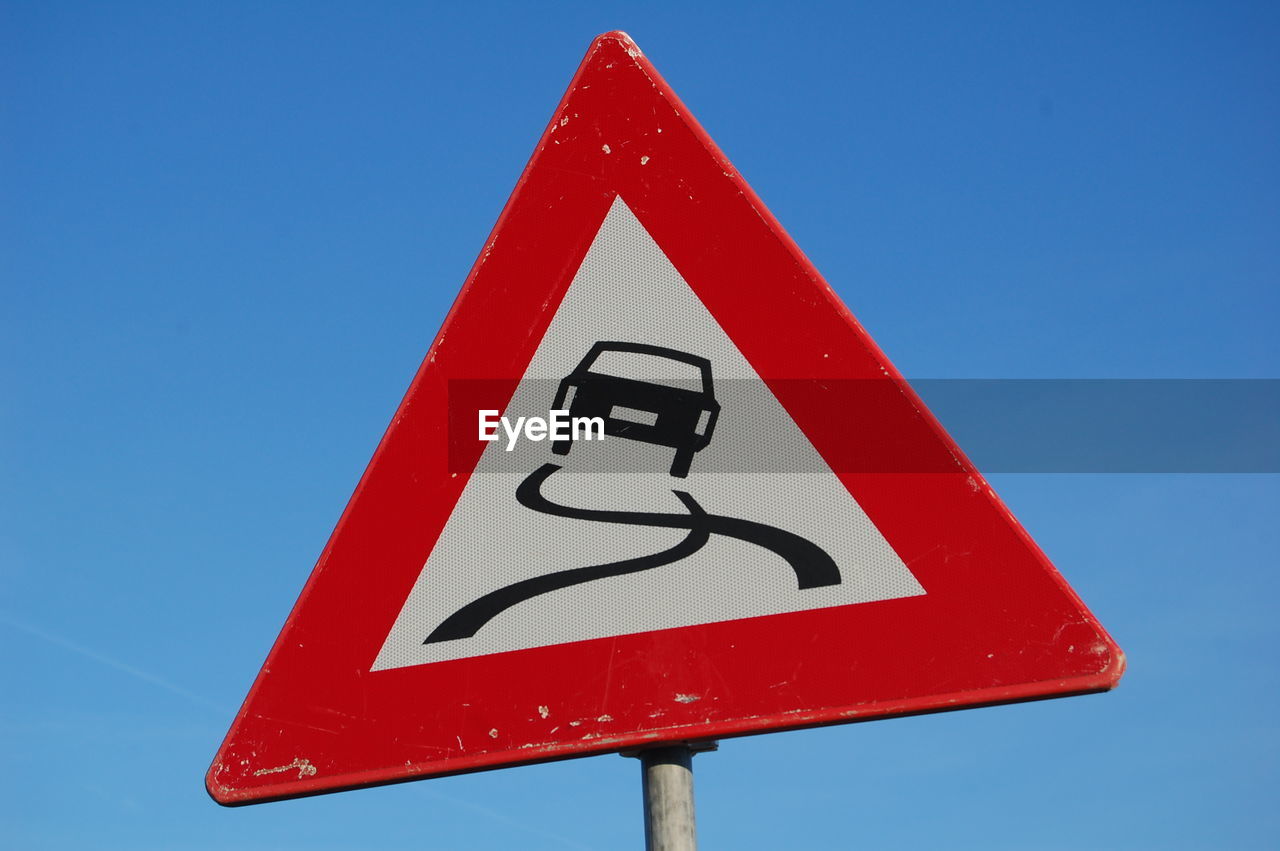Close-up of road sign against clear blue sky