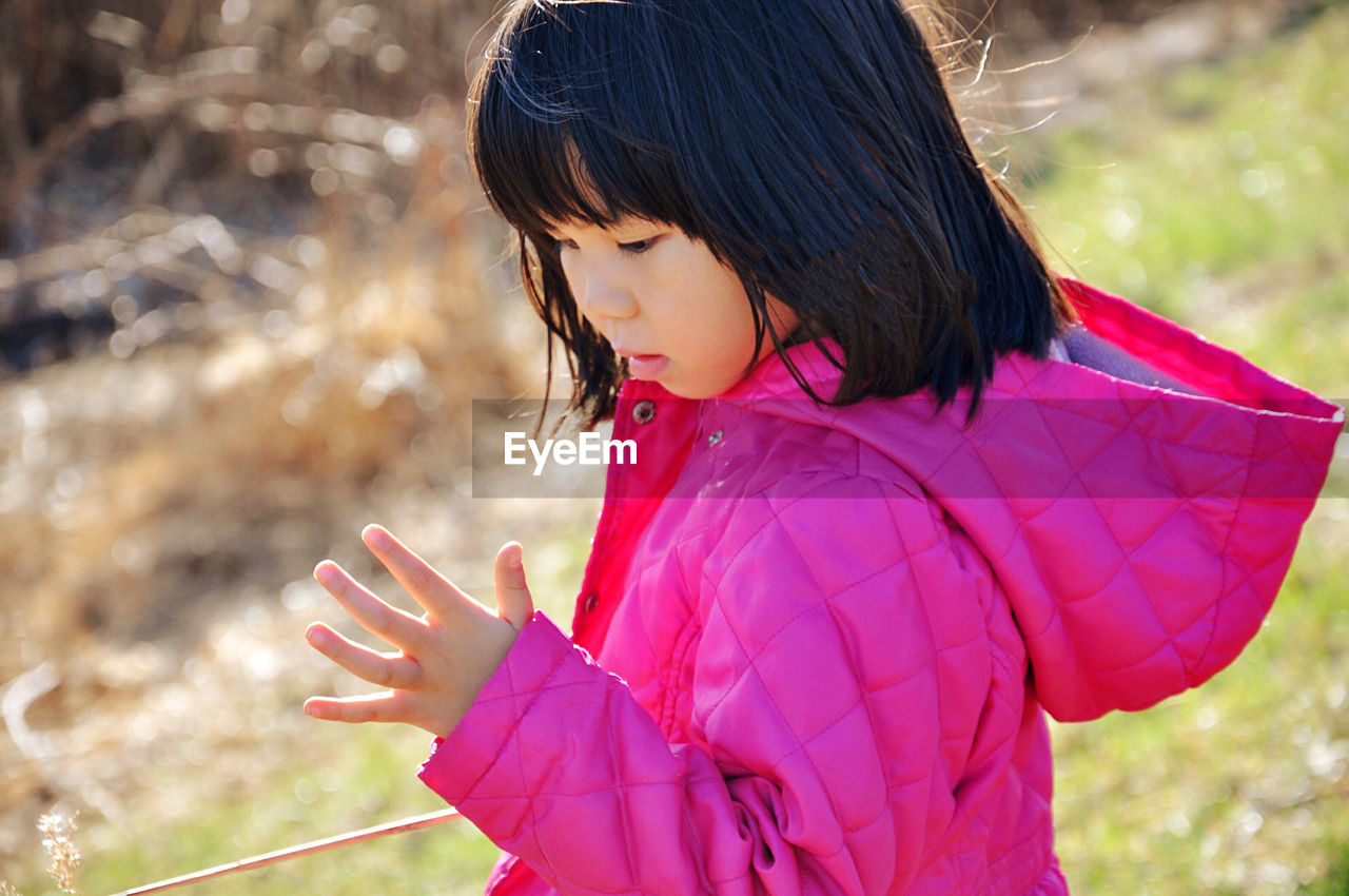 Side view of girl in pink cloth standing outdoors